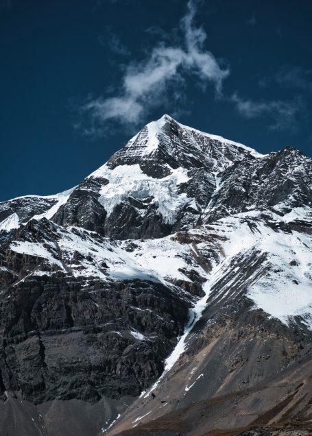 Schneebedeckter Gipfel eines Berges unter blauem Himmel mit Wolken.