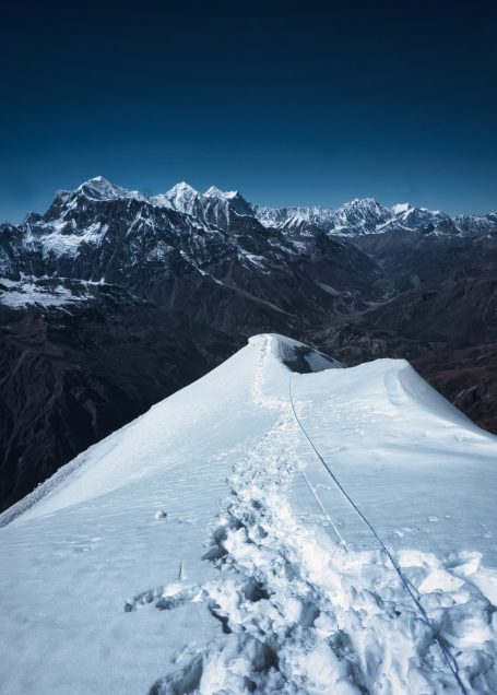 Schneebedeckte Bergspitze mit Blick auf umliegende Gipfel und Täler.