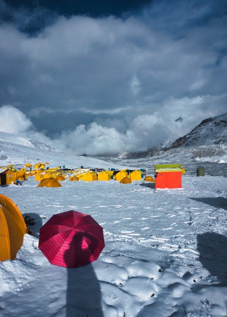 Bunte Zelte und ein roter Regenschirm in einer schneebedeckten Landschaft.