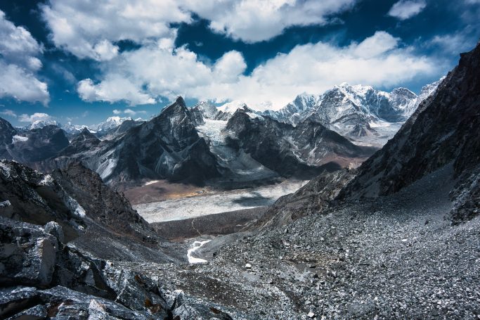 Berglandschaft mit schneebedeckten Gipfeln unter einem bewölkten Himmel.