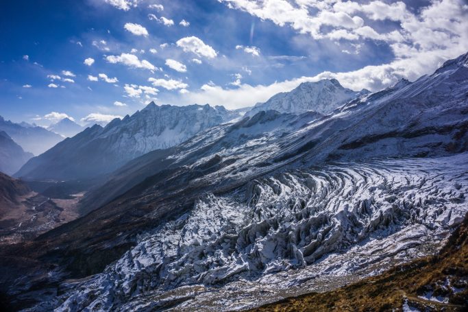 Schneebedeckte Berge unter einem klaren blauen Himmel mit Wolken.