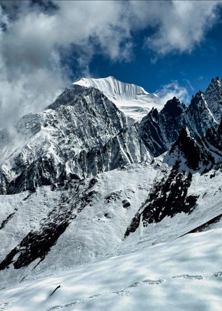 Schneebedeckte Berge unter einem klaren blauen Himmel mit einigen Wolken.