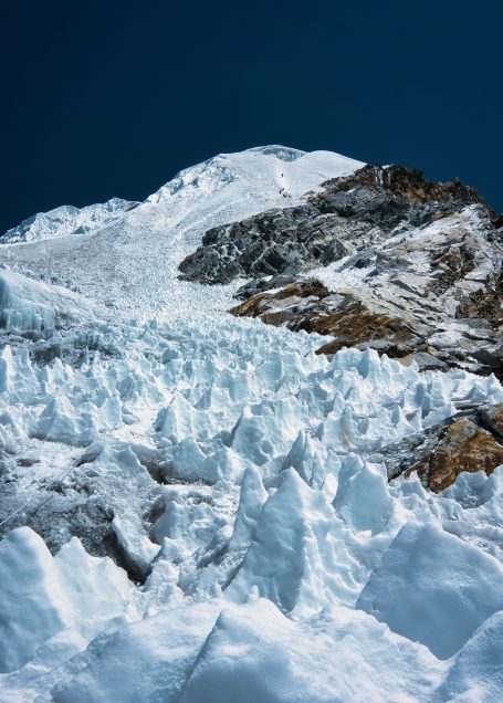 Schneebedeckter Berg mit Eiskristallen und klarem, blauem Himmel.