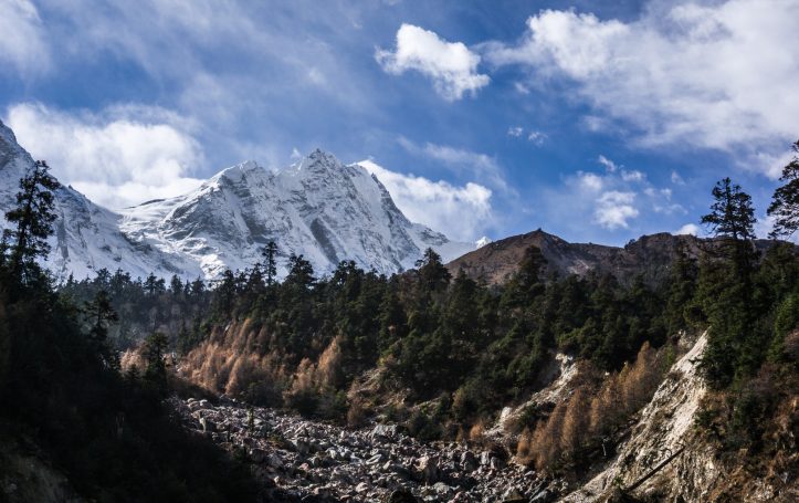 Schneebedeckte Berge über einem steilen Tal mit bewaldeten Hängen.