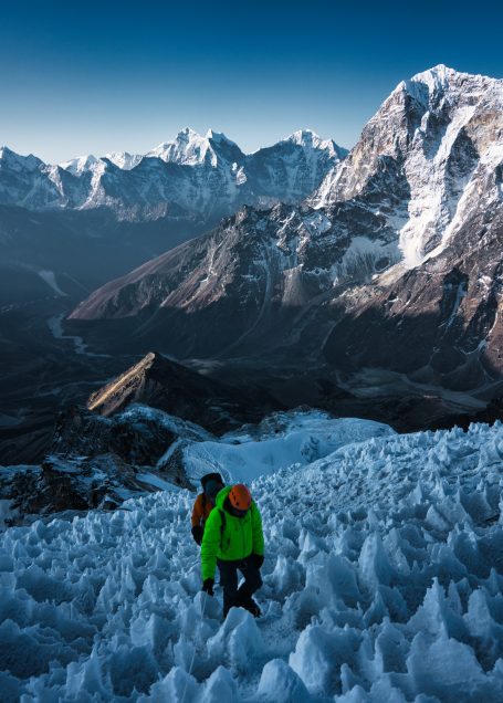 Bergsteiger in neonfarbigen Jacken, umgeben von Gletschern und schneebedeckten Bergen.