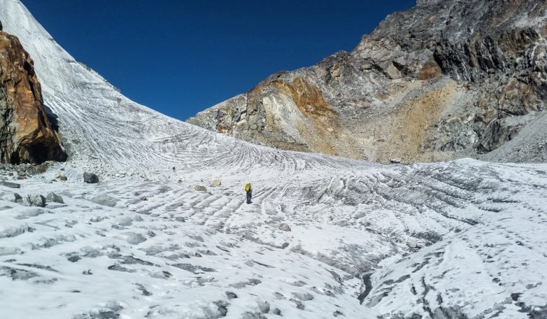 Schneebedeckte Berglandschaft mit Wanderern in der Ferne unter klarem, blauem Himmel.