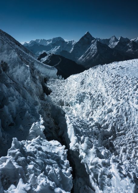 Berglandschaft mit schneebedeckten Gipfeln und einem Gletscher im Vordergrund.