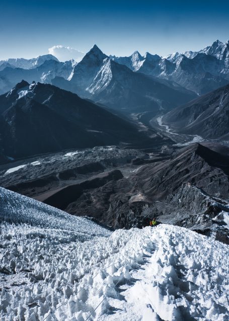 Schneebedeckte Berge mit dramatischer Landschaft und klaren Himmel im Hintergrund.