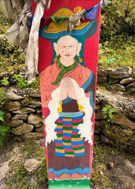 Bunte Wandmalerei eines spirituellen Führers mit gefalteten Händen und traditioneller Kleidung.