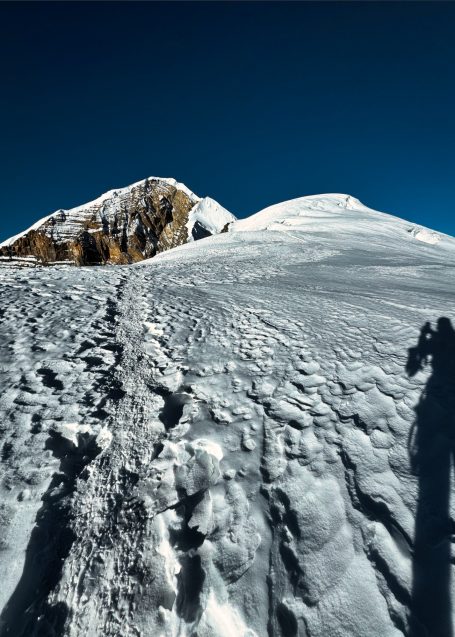 Schneebedeckte Gipfel mit klar blauem Himmel und Fußspuren im Schnee.