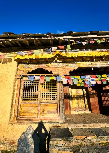 Fachwerkhaus mit bunten Gebetsfahnen und klarem blauen Himmel.