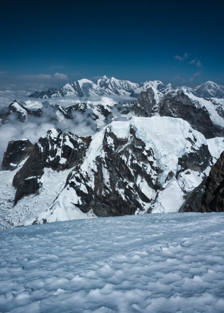 Schneebedeckte Berglandschaft mit Gipfeln und blauem Himmel.