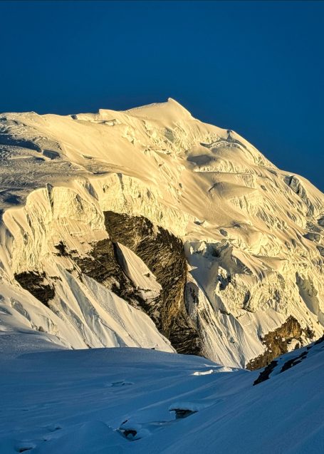 Helle, schneebedeckte Bergspitze unter blauem Himmel.