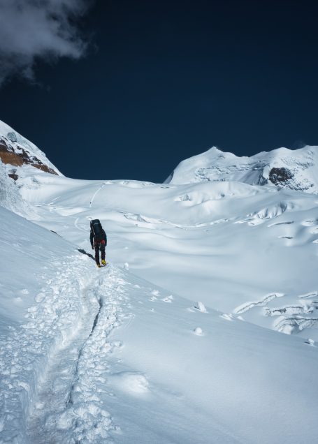 Ein Bergsteiger im Schnee auf einem weiten, unberührten Hochgebirgsfeld.