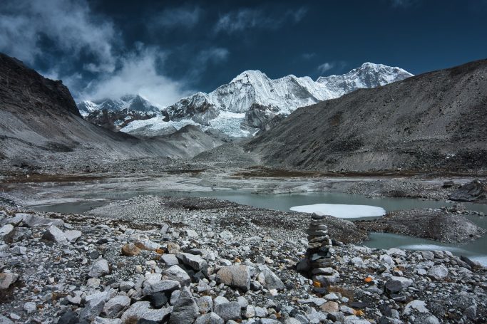 Schneebedeckte Berge und ein Gletschersee in einer felsigen Landschaft.