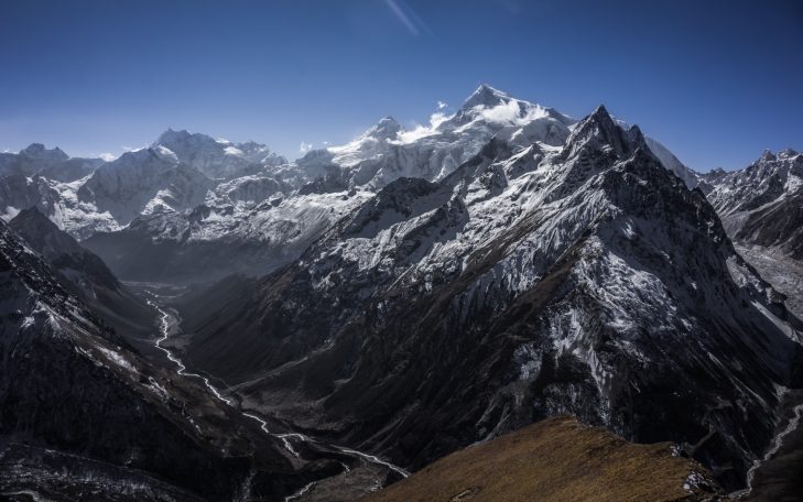 Schneebedeckte Berge unter klarem blauen Himmel mit einem Tal im Vordergrund.