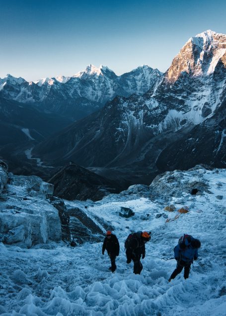 Drei Bergsteiger wandern über schneebedeckte Hänge in einer Berglandschaft.