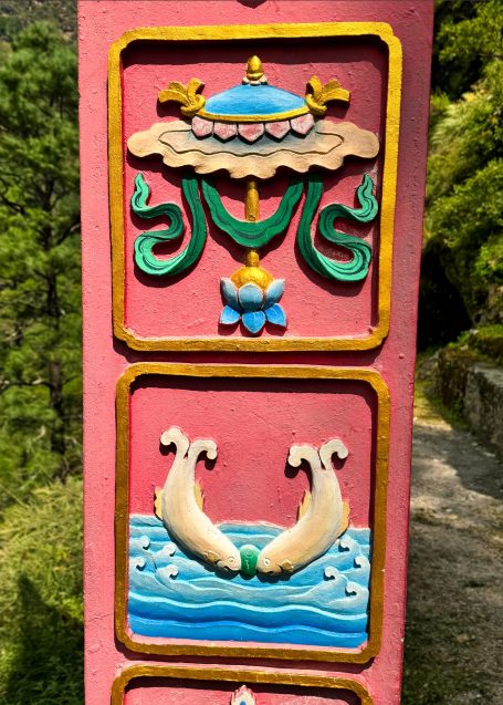 Bunt gestaltetes Relief mit Wolken, Wasser und stilisierten Fischen auf pinkem Hintergrund.