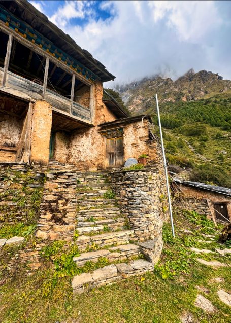 Verfallenes Gebäude mit Steintreppe und Bergen im Hintergrund.