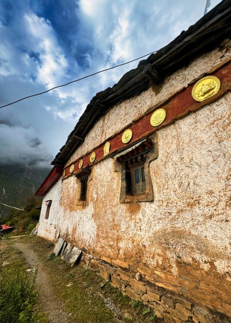 Traditionelles Haus in ländlicher Umgebung mit Fenstern und Schriftzügen.