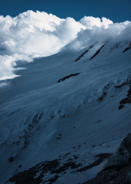 Schneebedeckte Berglandschaft unter dramatischen Wolken.