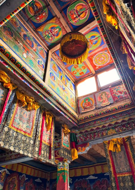 Bunt dekorierter Innenraum eines buddhistischen Tempels mit kunstvollen Wandmalereien.