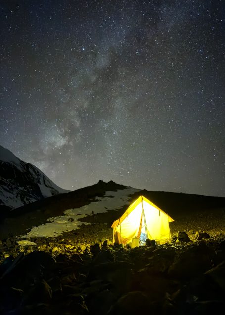 Ein leuchtendes Zelt unter einem sternklaren Nachthimmel mit Milchstraße.