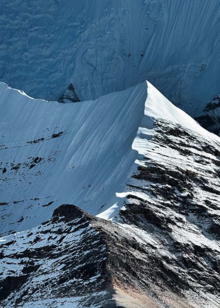 Schneebedeckte Bergspitze mit steilen Hängen in einem klaren Himmel.