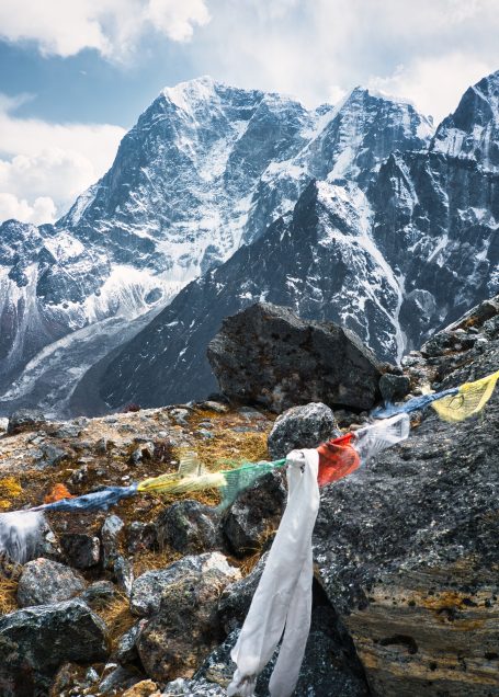 Berge mit schneebedeckten Gipfeln und bunten Gebetsfahnen im Vordergrund.