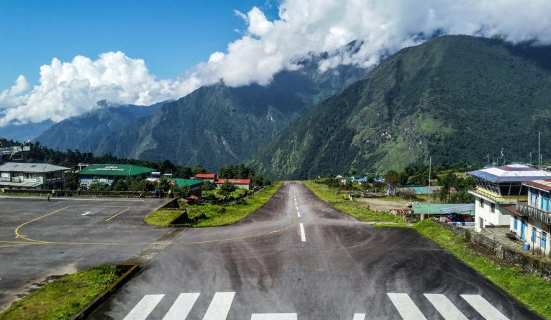 Landeplatz mit einer Start- und Landebahn, umgeben von Bergen und Wolken.