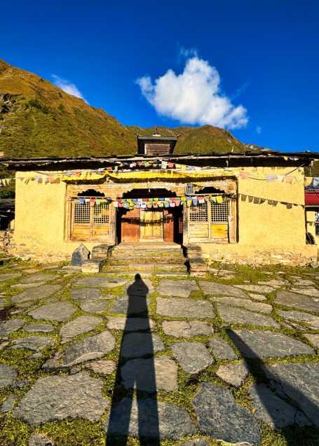 Traditionelles Gebäude mit bunten Fahnen, Schatten einer Person, blauem Himmel.
