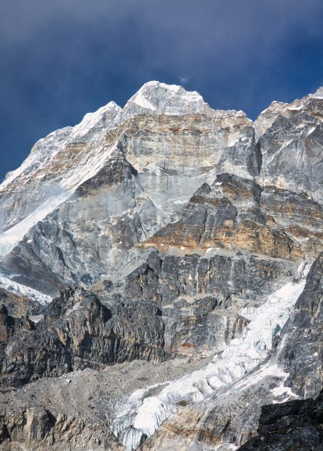Hohe Felsen mit schneebedecktem Gipfel und grauem Fels im Hintergrund.