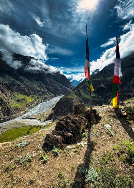 Aussicht auf einen Fluss zwischen hohen Bergen und Fahnen im Vordergrund.