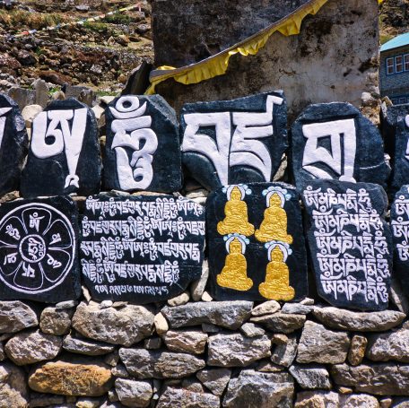 Bunte Steintafeln mit tibetischen Schriftzeichen und buddhistischen Symbolen.