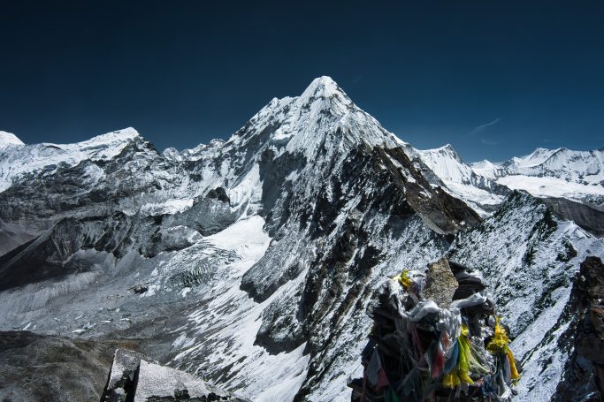 Hoher schneebedeckter Gipfel unter klarem Himmel, umgeben von weiteren Bergen.