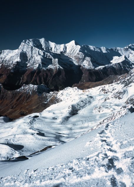 Schneebedeckte Berge mit schroffen Gipfeln und klar blauem Himmel.