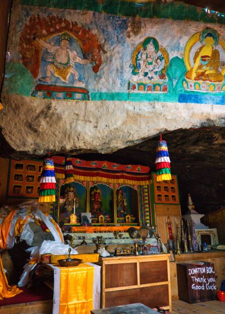 Buddhistische Höhlenkapelle mit bunten Wandmalereien und einem Altar.